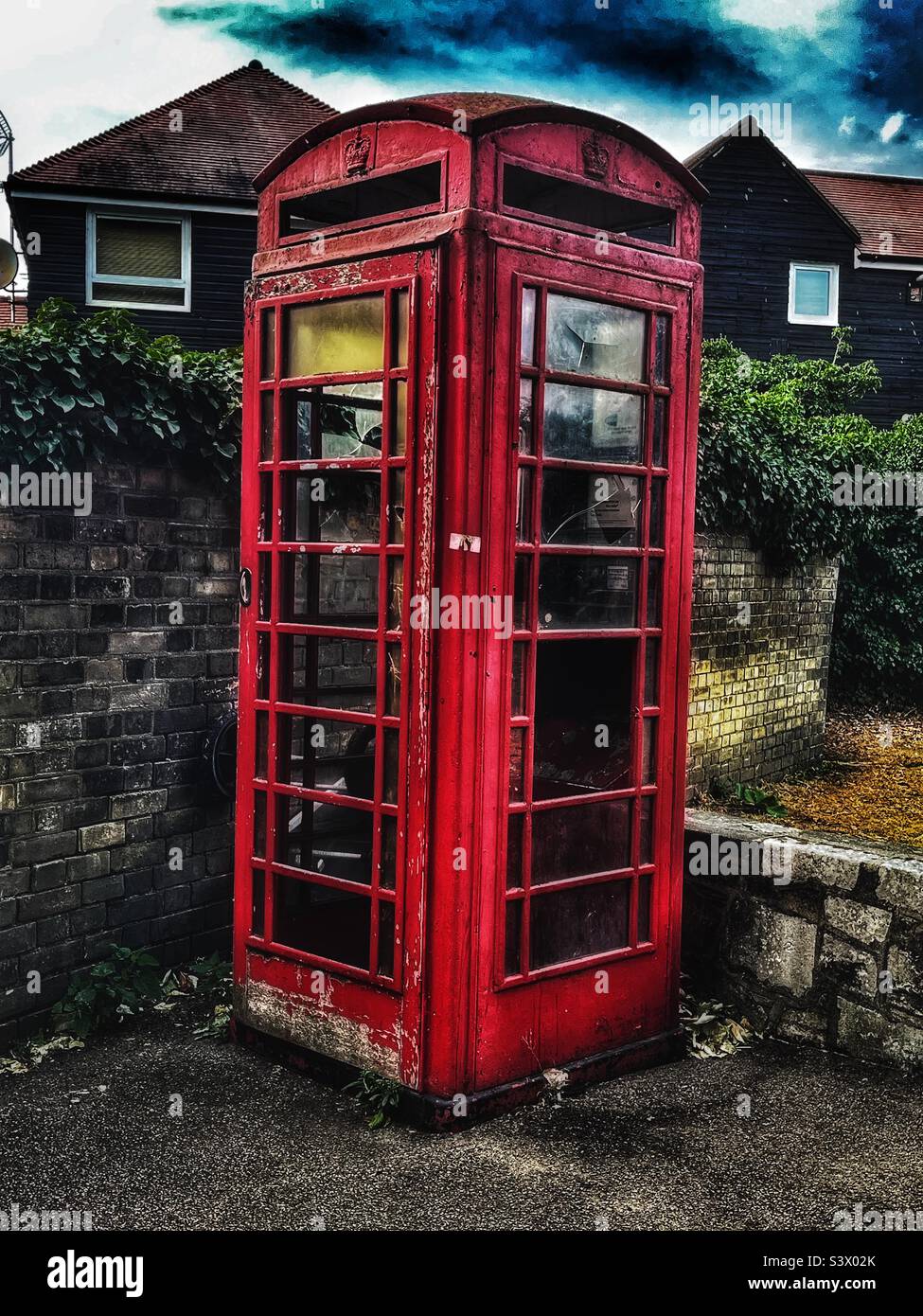 British Telephone Box in faded glory outside Waltham Abbey Stock Photo