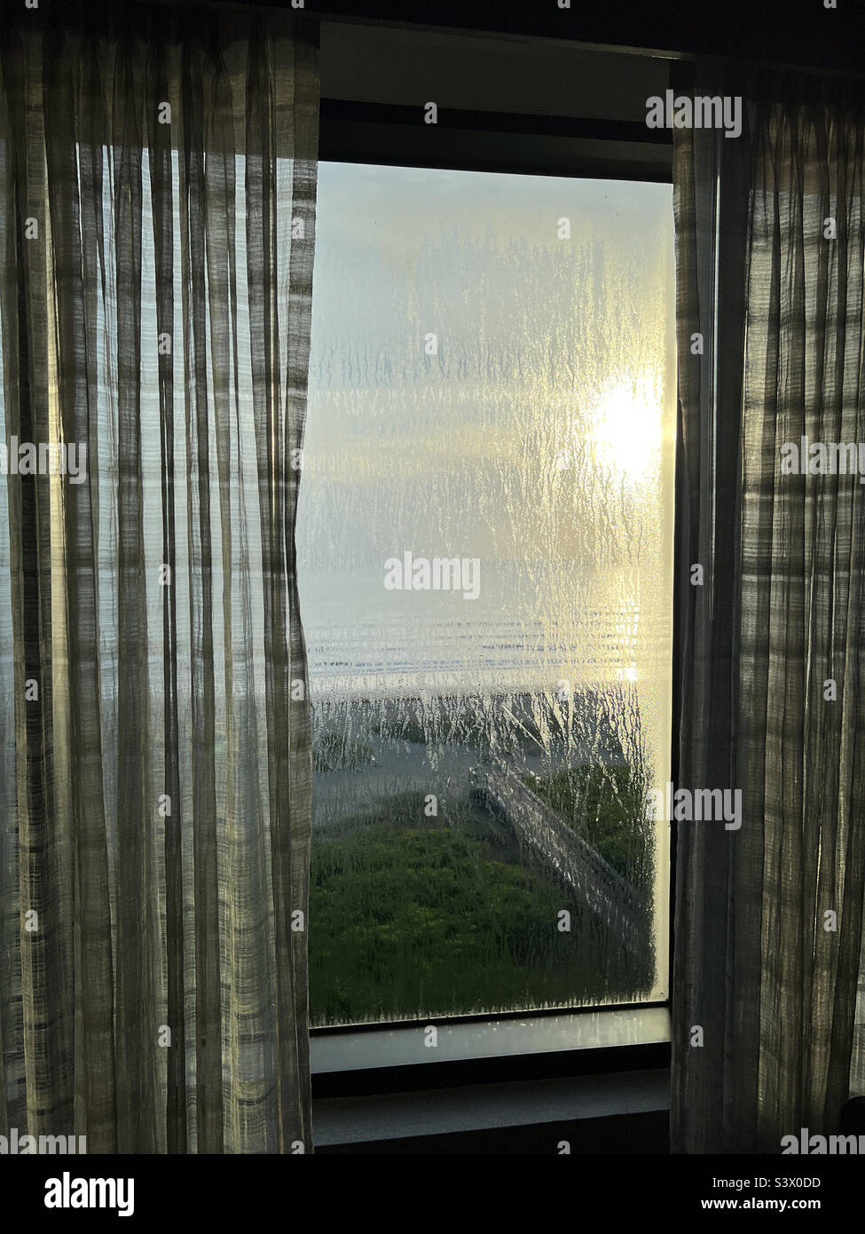 Morning moisture on window overlooking beach Stock Photo