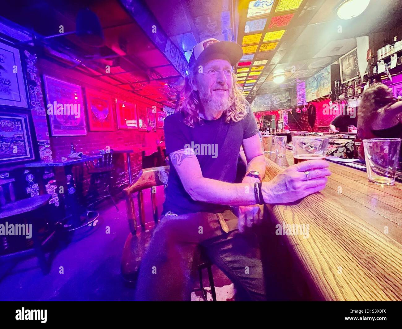 A man has a drink at a rock bar in Denver - Smartphone Captured Stock Image