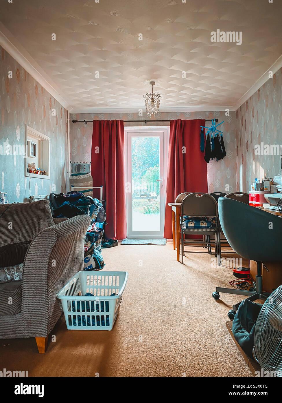View down a living room towards the back patio garden door at the end of the room. - Smartphone Captured Stock Image