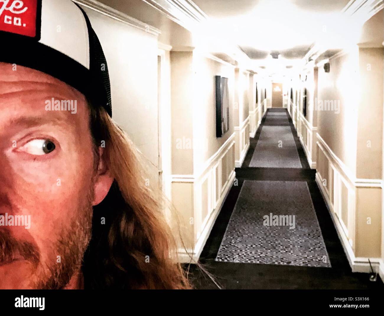 A man looks back at the long hallway of a hotel in Denver Colorado - Smartphone Captured Stock Image