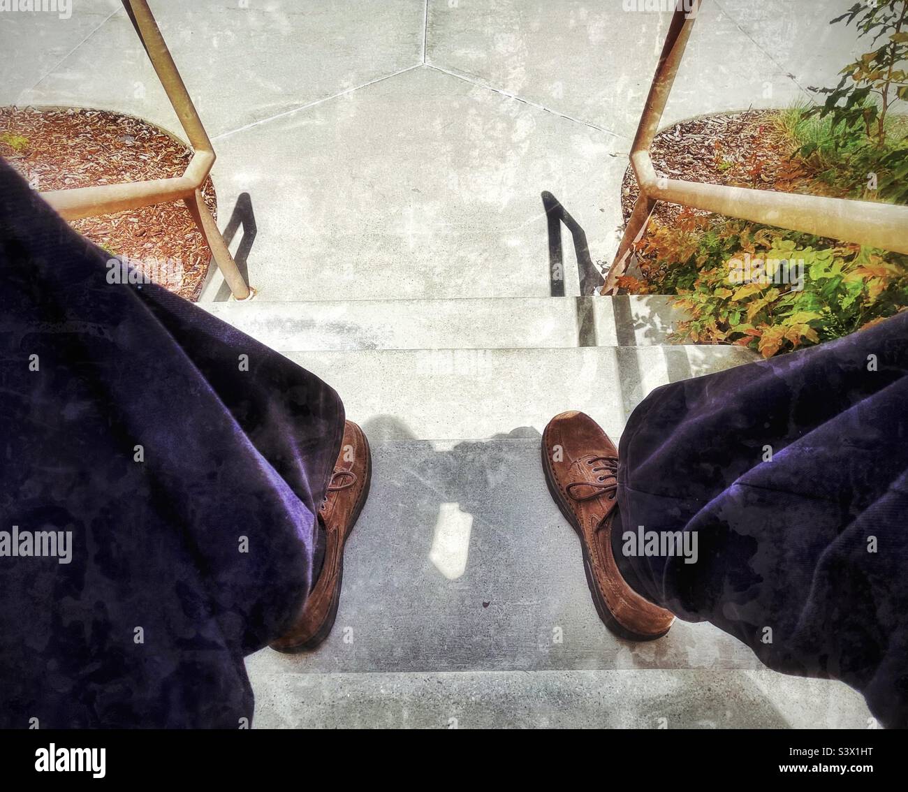 Man in Sunday dress sitting on outdoor steps at a local church in Utah, USA. Casually relaxing on a sunny day, image is shot while sitting looking down the steps between the man’s knees-Perspective! - Smartphone Captured Stock Image