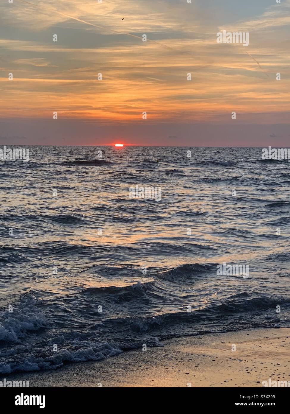 The Sun goes down in the sea creating shades of colors giving unique feelings and internal peace. Stock Photo