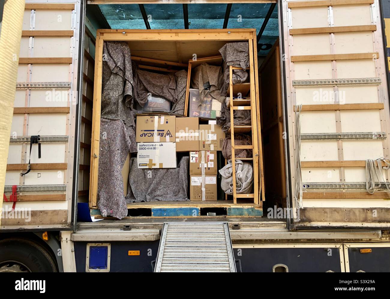 Removal lorry with boxes of household items and furniture packed into storage container with loading ramp - Smartphone Captured Stock Image