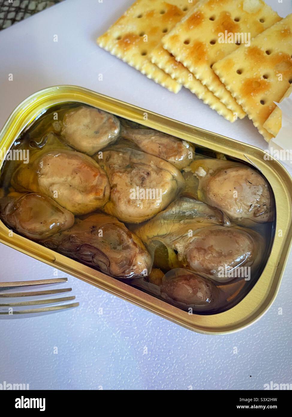 Close-up of an open tin of smoked oysters and saltine crackers, 2022, USA Stock Photo