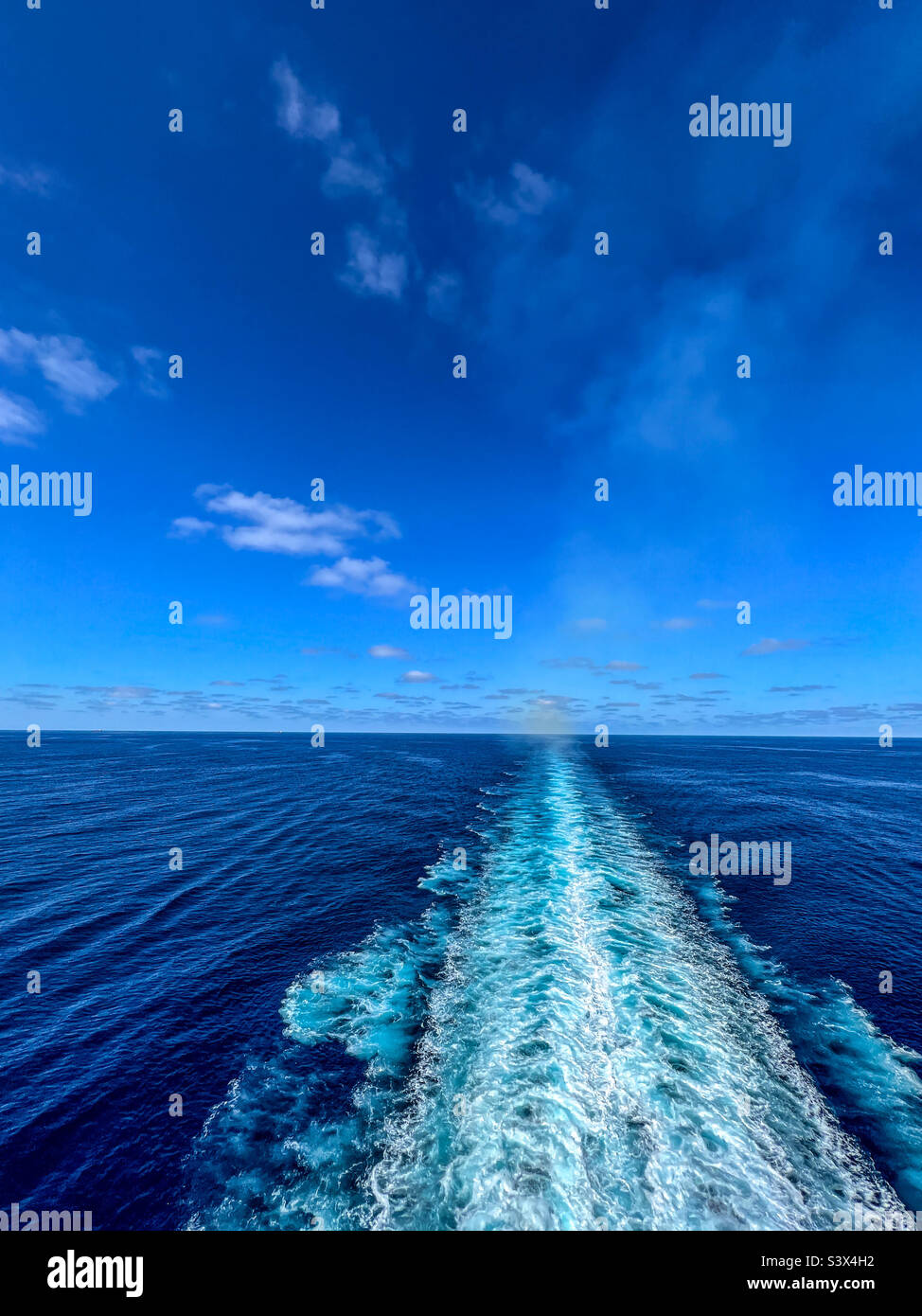 Cruise ship wake stretching from the stern to the blue sky horizon across the still North Atlantic Ocean - Smartphone Captured Stock Image