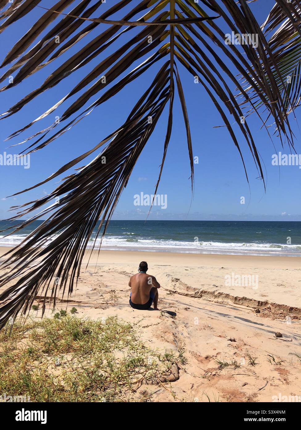 A man sitting on the beach in solitude. Stock Photo