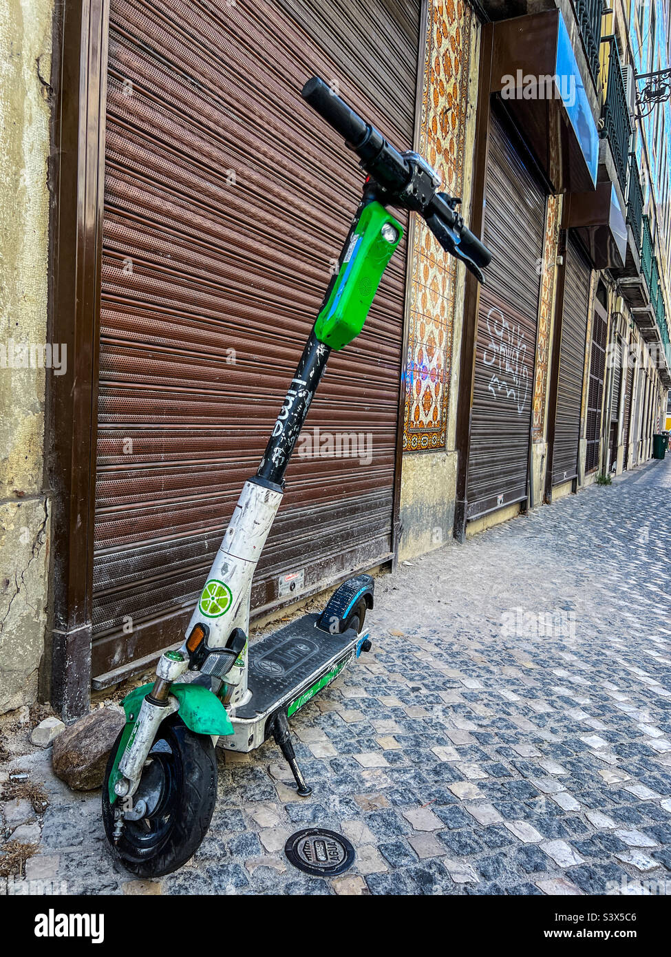 Battered electric scooter parked up in derelict area of Lisbon Stock Photo