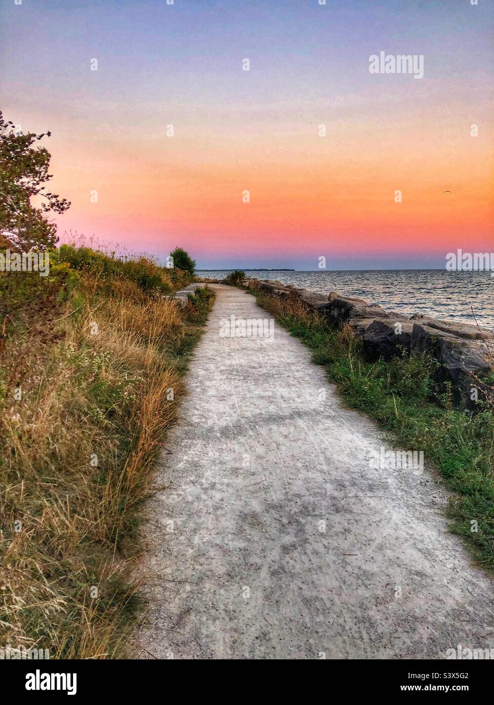 A gravel path leads to a beautiful sunset. Stock Photo