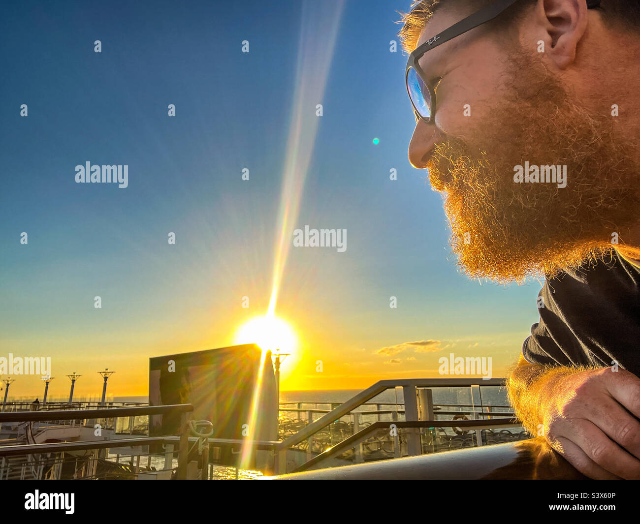 Man with beard looking on into sunset on cruise Stock Photo