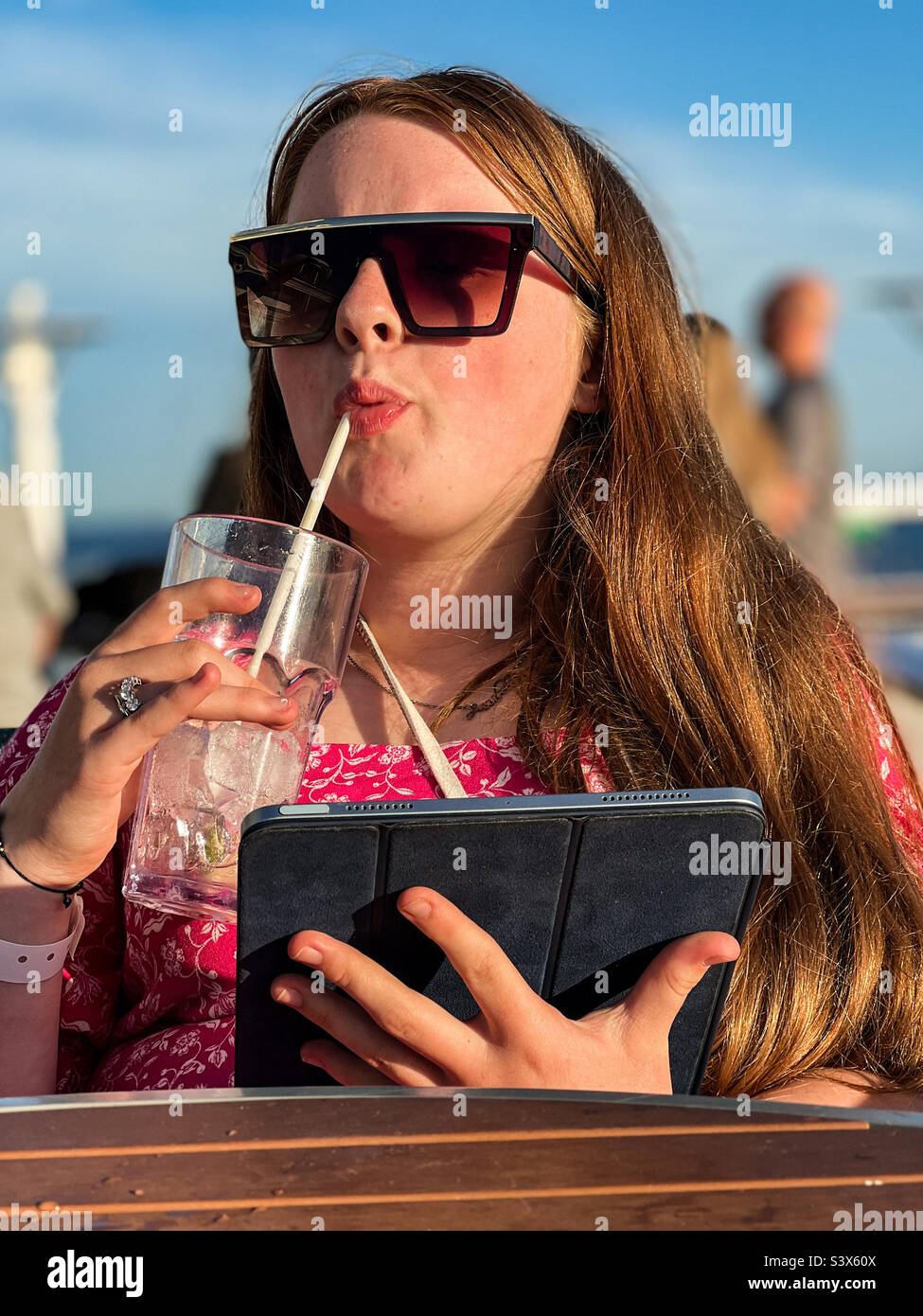 Young woman drinking lemonade while holding an iPad - Smartphone Captured Stock Image