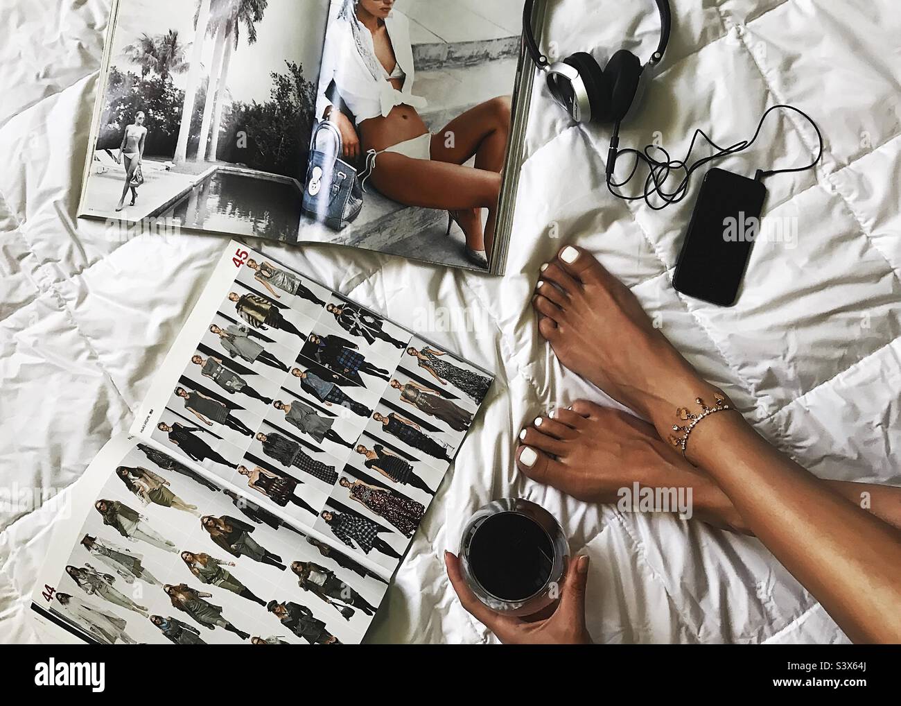 Leisure and relaxation at home with red wine and fashionable magazines and music - Smartphone Captured Stock Image