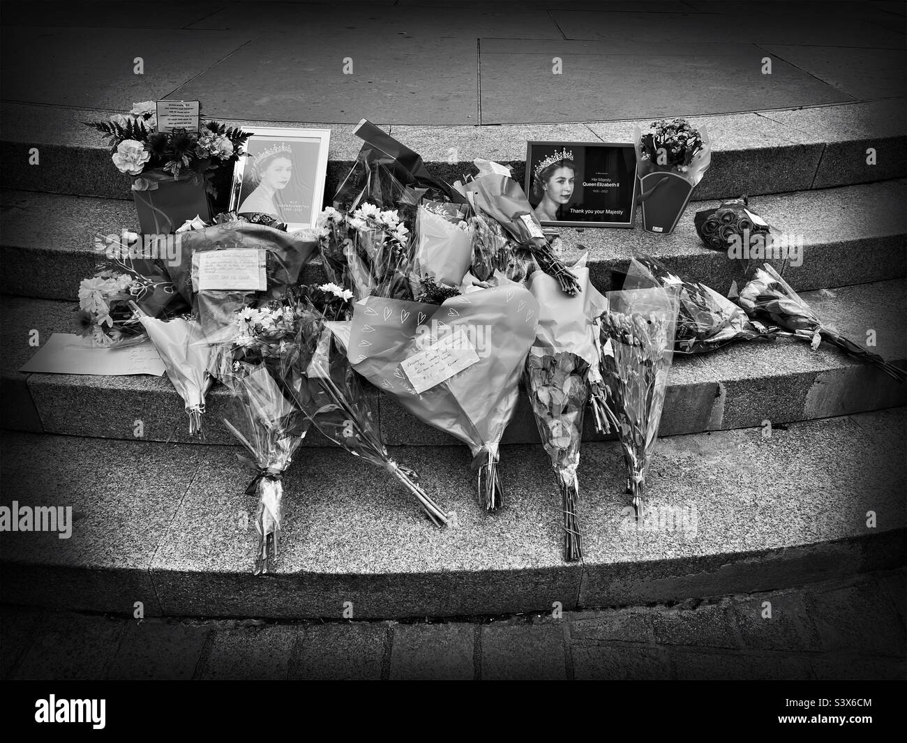Flowers and cards left to commemorate the death of Queen Elizabeth II, Planestanes, High Street, Dumfries town centre, Scotland.  Monochrome image. - Smartphone Captured Stock Image