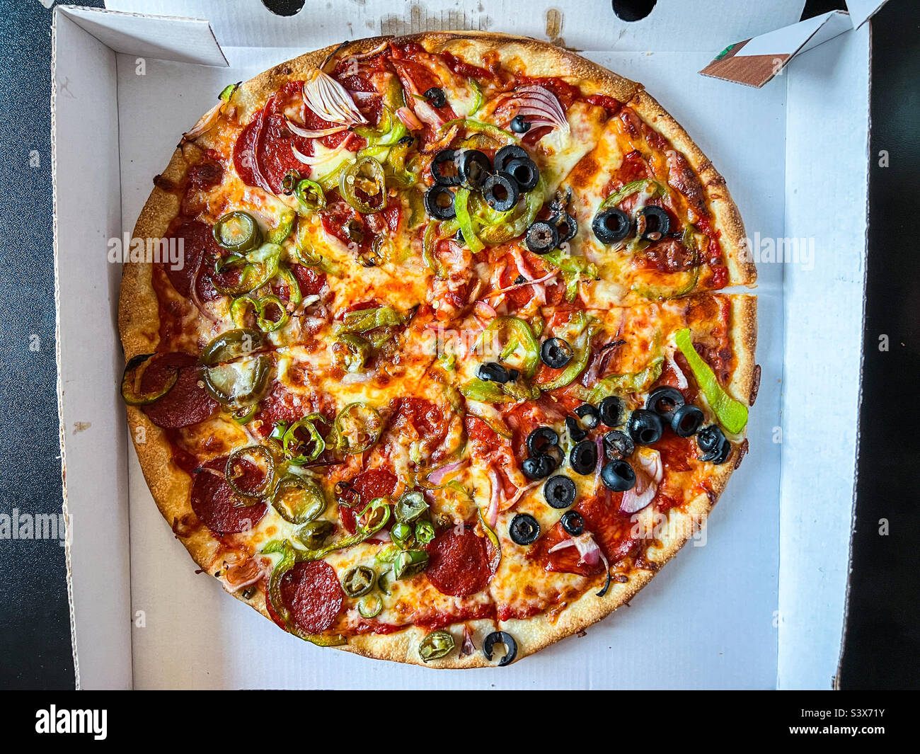 Mixed meat and veggie toppings on takeaway pizza Stock Photo