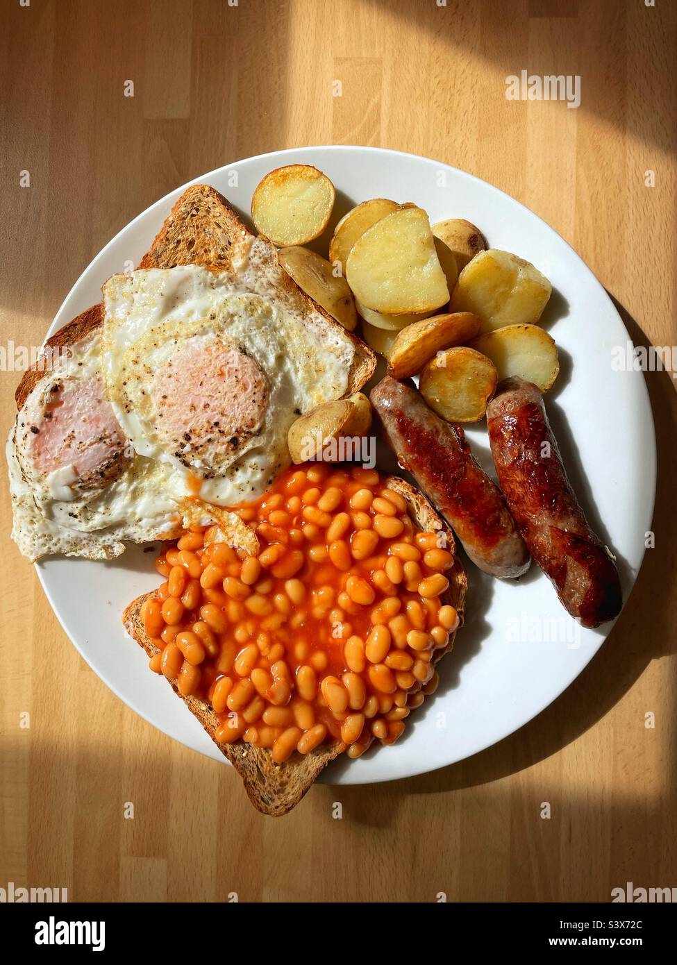 Brunch / breakfast food. Fried eggs, potatoes, beans and sausages. Stock Photo