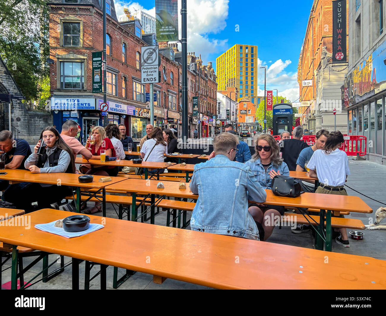 Young people enjoying a refreshing drink on New Briggate in Leeds city centre Stock Photo