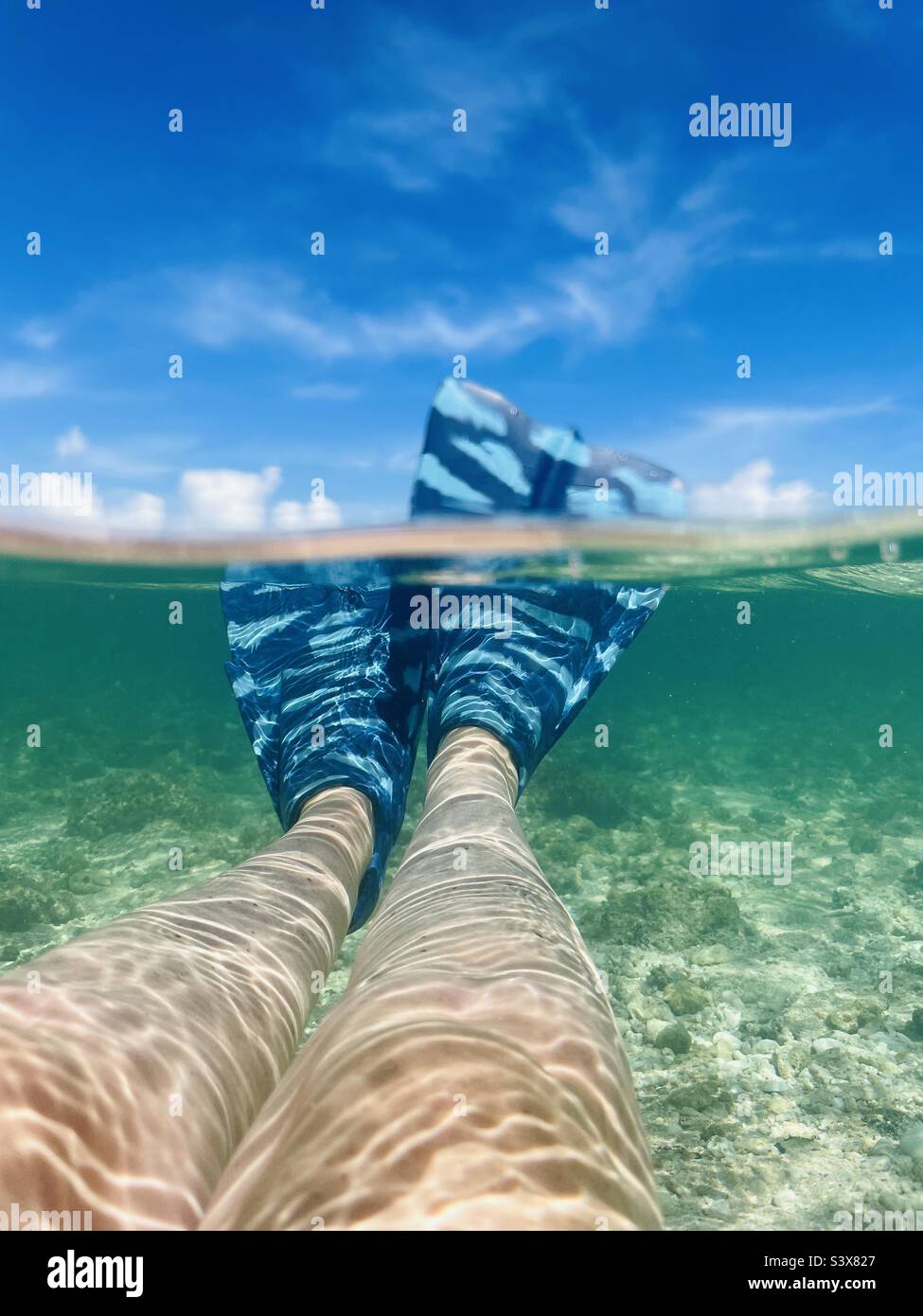 A female snorkeler floating on her back with her fins out in tropical water. Tavarua island, Fiji. - Smartphone Captured Stock Image