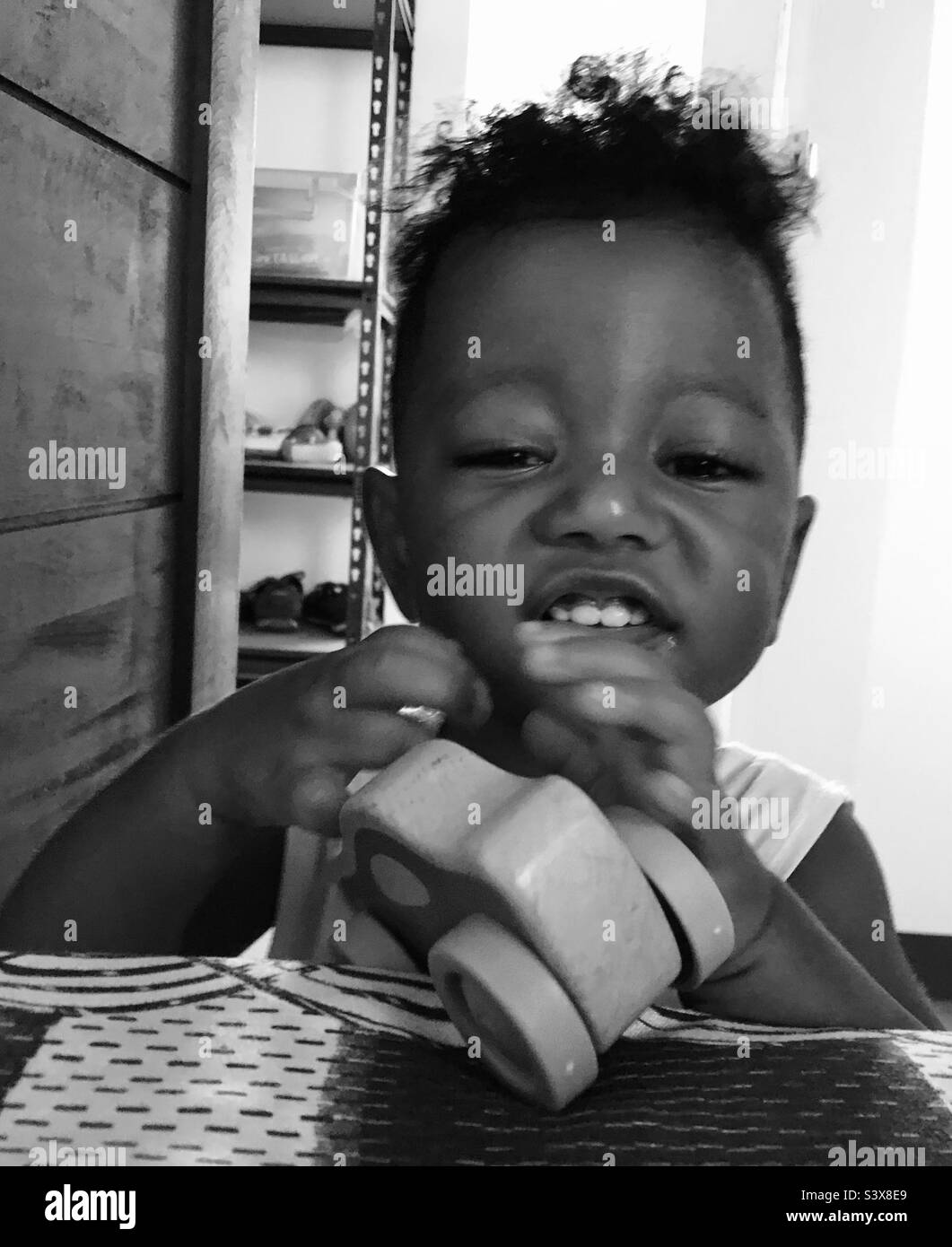 Mestizo, black and Filipino baby boy playing with wooden car toy Stock Photo