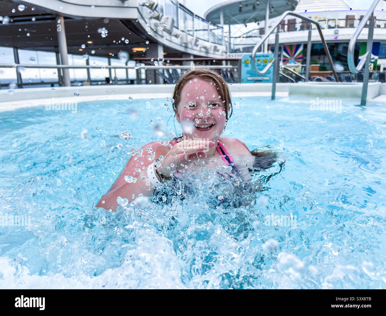 Young teenage girl splashing water while in a jacuzzi Stock Photo