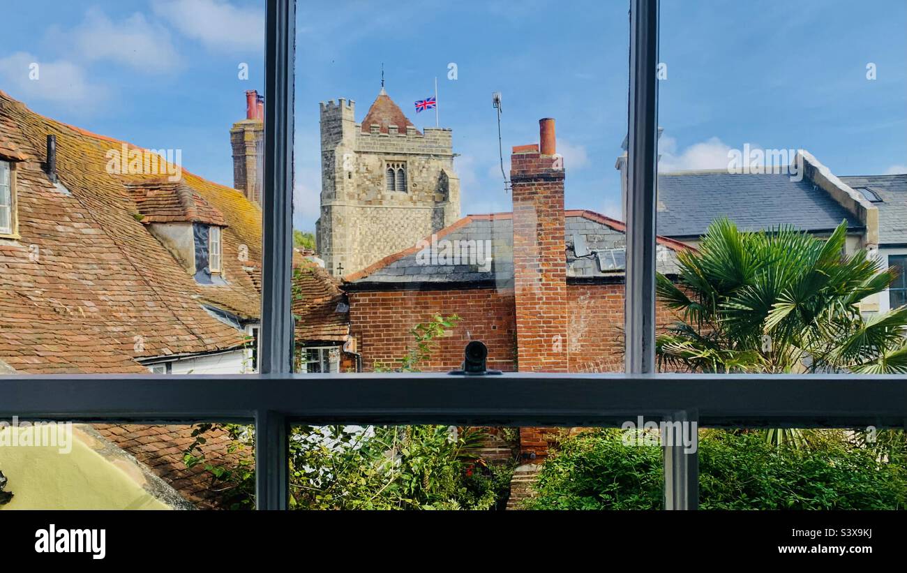 A sash window view of Hastings Old Town rooftops and church just days after the passing of the Queen ERII withe Union Flag at half mast - Smartphone Captured Stock Image