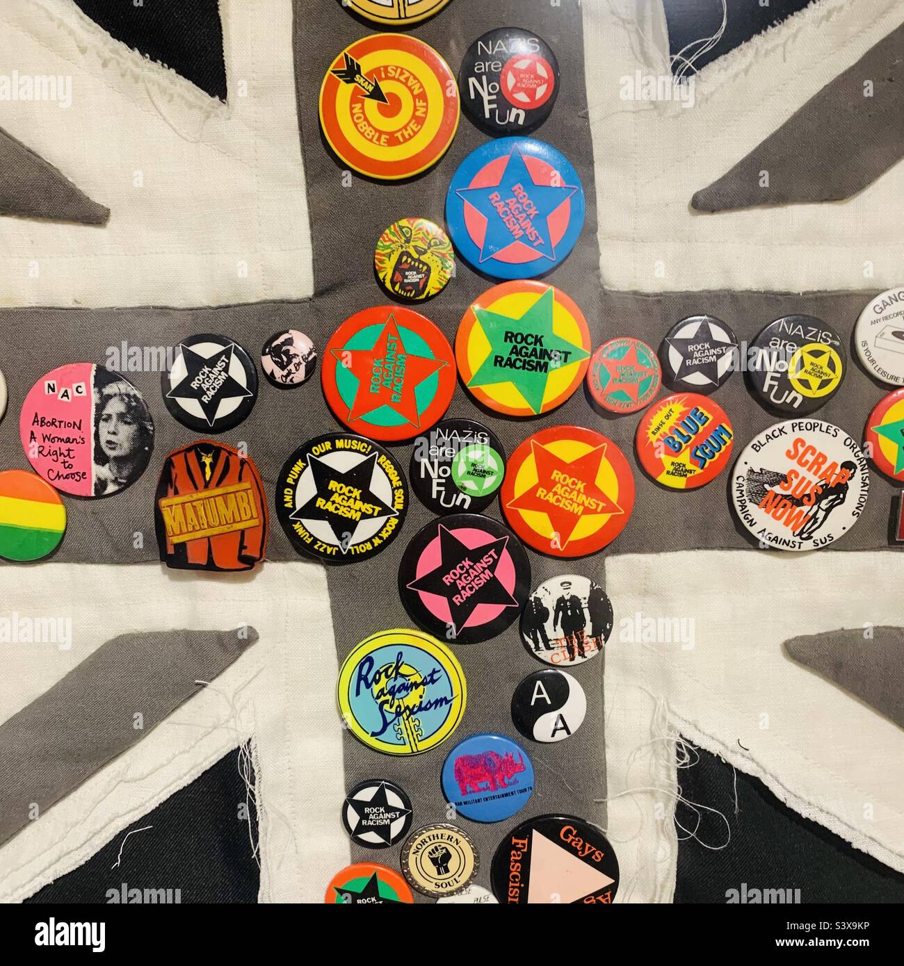 Anti racism anti nazi campaign groups badges from the 1970’s pinned on a monochrome Union Flag artwork collection- British Britain Stock Photo