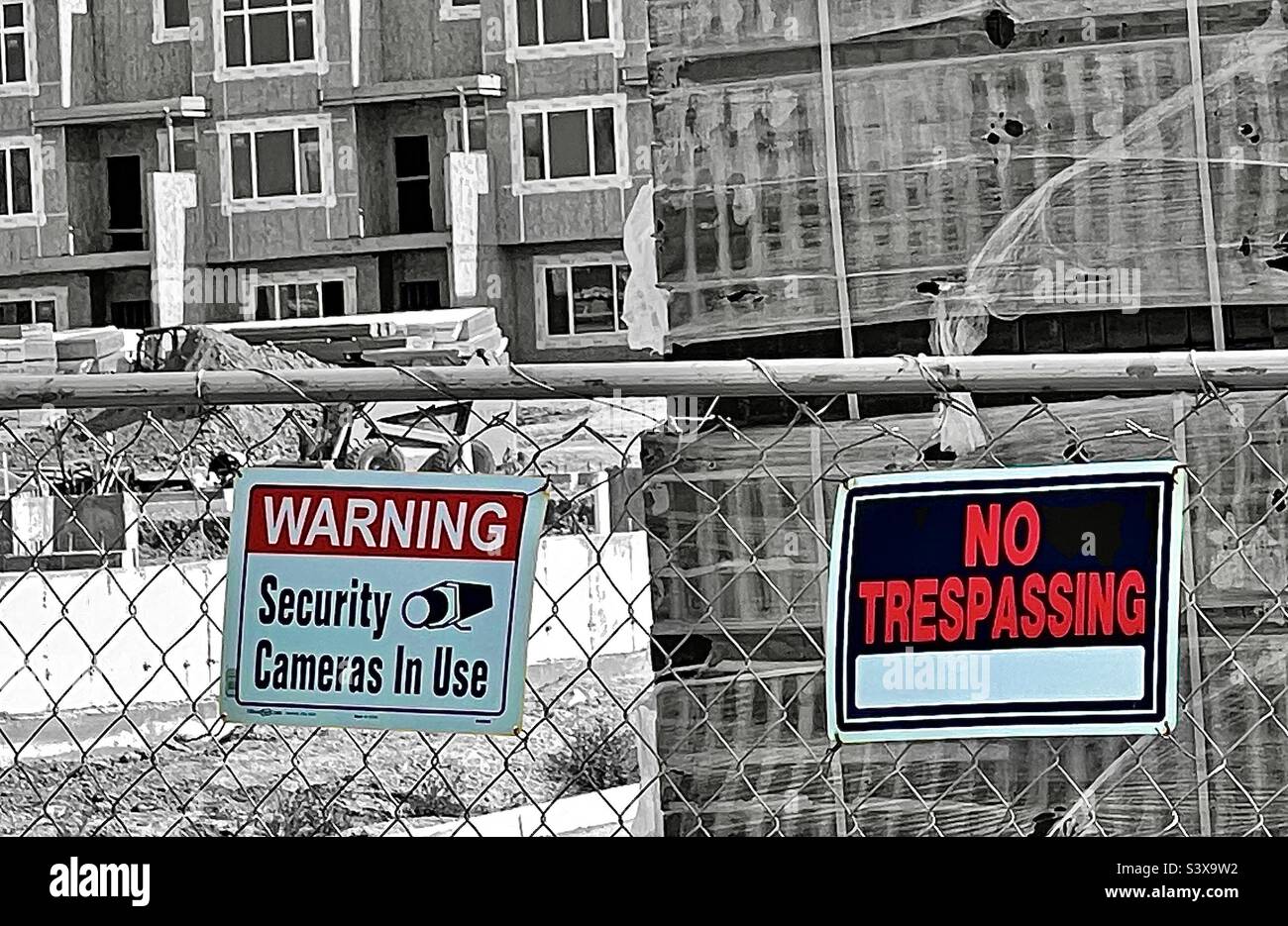 A fenced in construction site, in Utah, USA with colorized signs posted warning of “Security Cameras In Use” and indicating “No Trespassing” allowed. - Smartphone Captured Stock Image