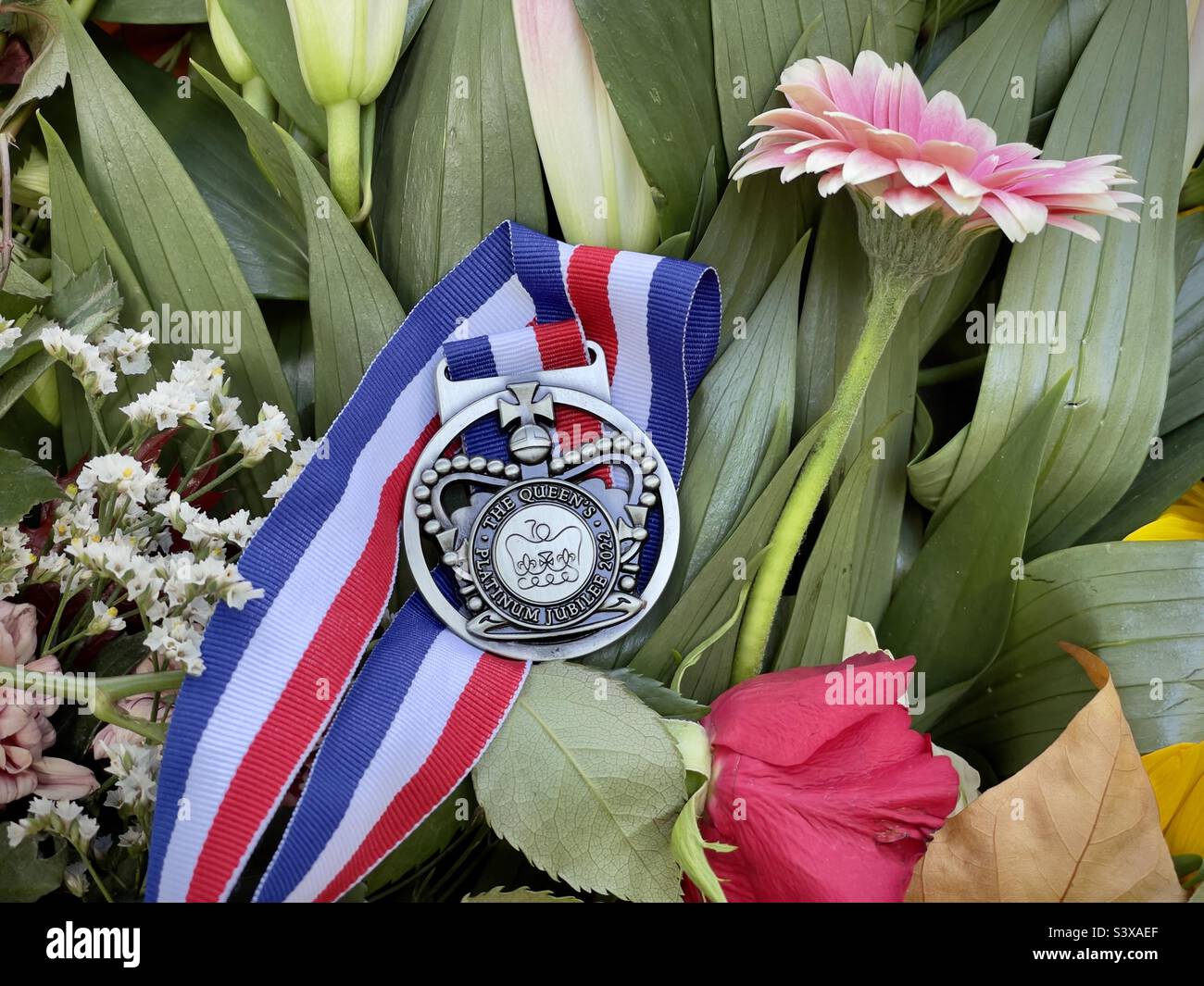 Platinum Jubilee medal amongst the flowers for The Queen, Green Park, London 17 September 2022 - Smartphone Captured Stock Image