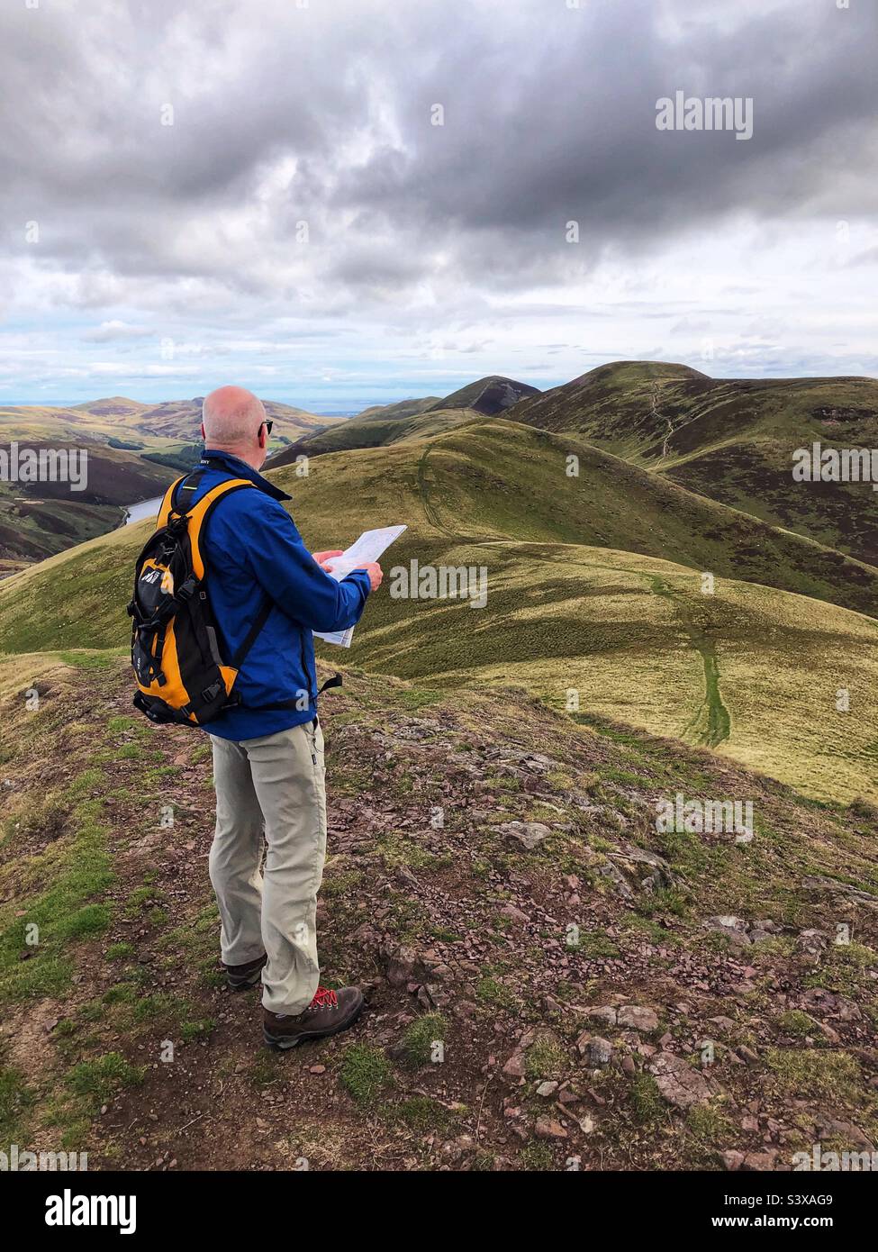 Mature man lost and reading a map in the Pentlands regional park with a view towards East Kip, Edinburgh Scotland - Smartphone Captured Stock Image