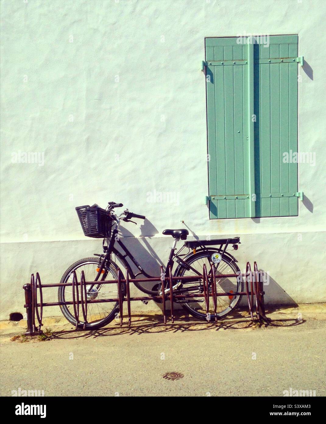 bicycle standing on a house facade with a green window - Smartphone Captured Stock Image
