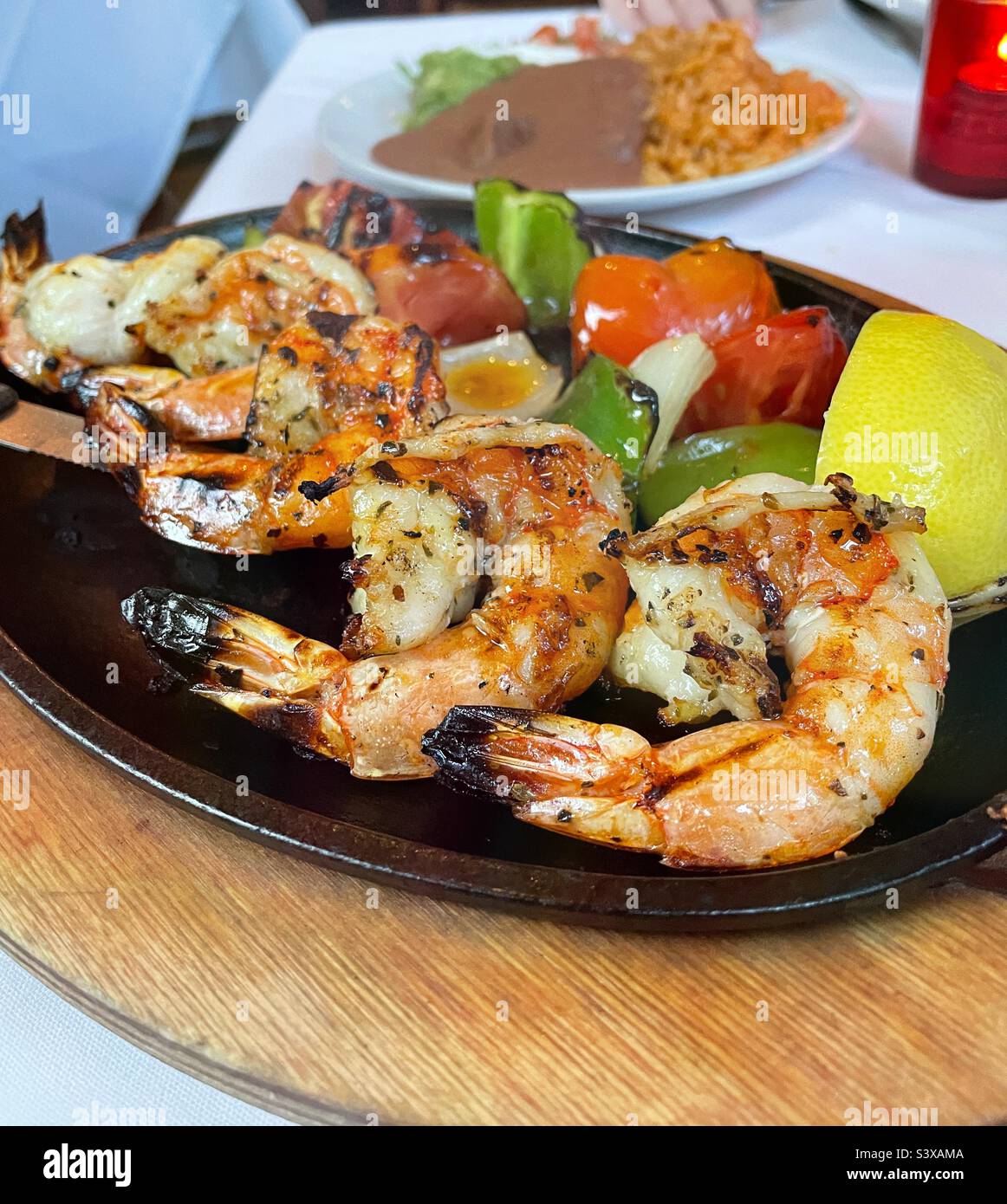 A gourmet grilled shrimp dinner with refried beans and yellow rice ...