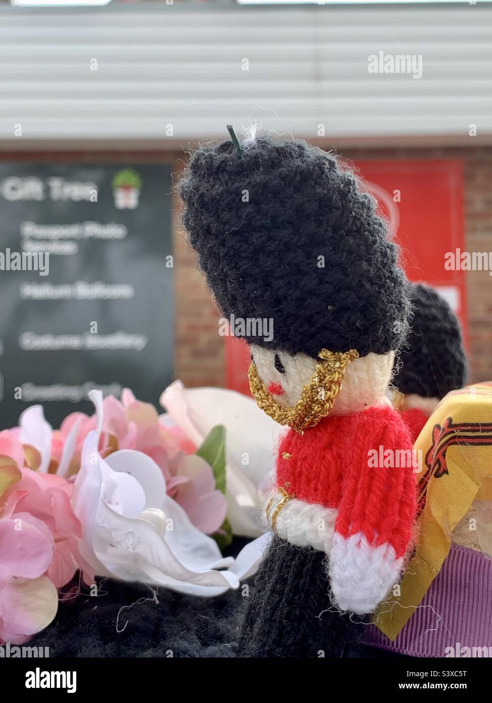 Ipswich, Suffolk, UK - 19 September 2022 : Mourning the death of Queen Elizabeth II. Crochet guardsman with head bowed on a Royal Mail post box. Stock Photo