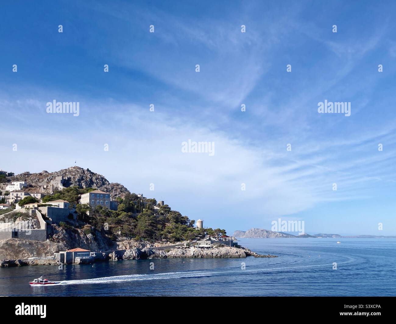 View of Hydra, Greece, with a boat and its wake in the water below - Smartphone Captured Stock Image