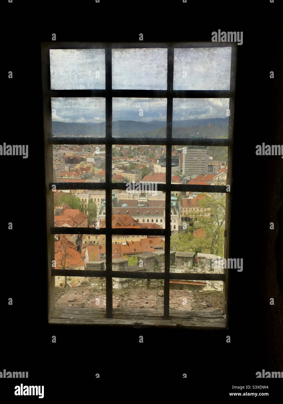 View of Ljubljana through a dirty old window on the climb up to Ljubljanski grad (Ljubljana castle), Slovenia. Stock Photo