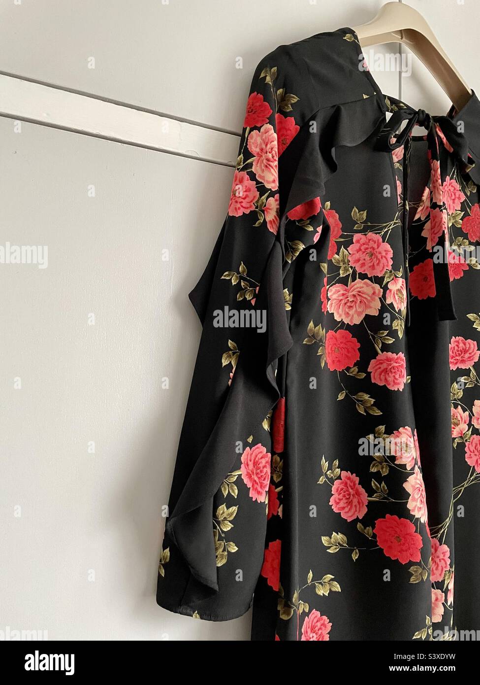 Photo taken of pretty floral dress hanging on bedroom cupboards, ready to put up for sale on preloved selling site. Stock Photo