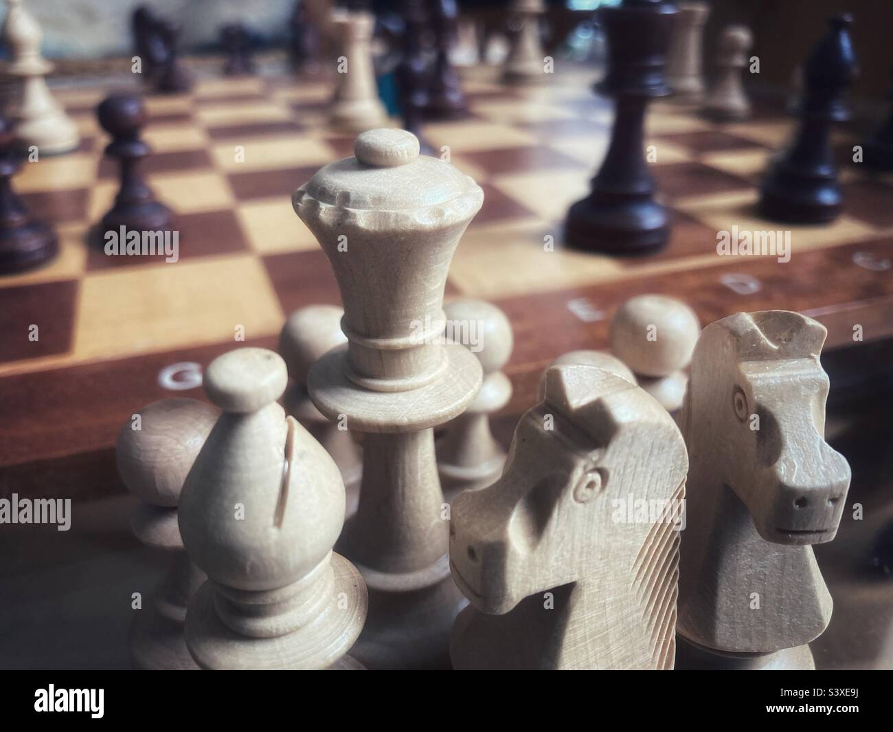 Chess pieces that were taken during a game on a board in the background Stock Photo
