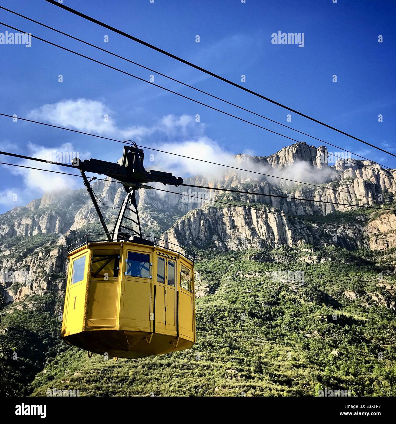 A tourist cable car heads up towards the monastery at Montserrat near Barcelona in Catalonia in Spain with the misty mountains behind - Smartphone Captured Stock Image