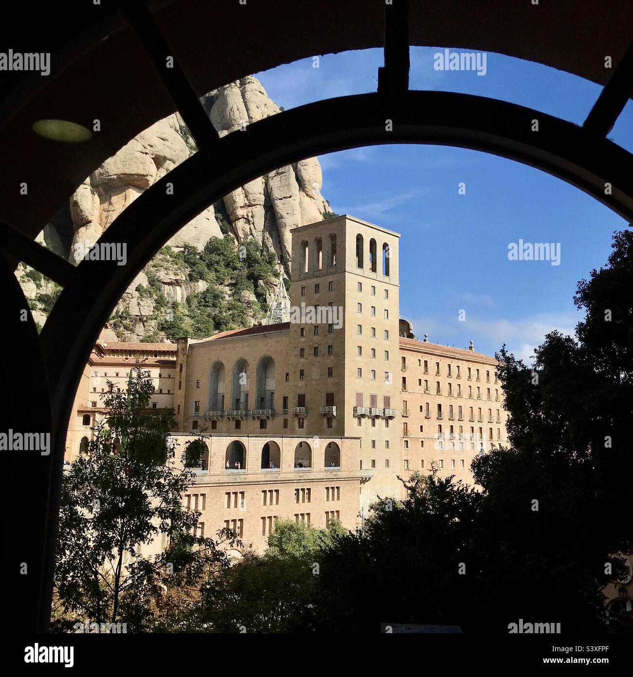 The monastery at Montserrat near Barcelona in Catalonia in Spain photographed from the funicular station tunnel across the valley - Smartphone Captured Stock Image