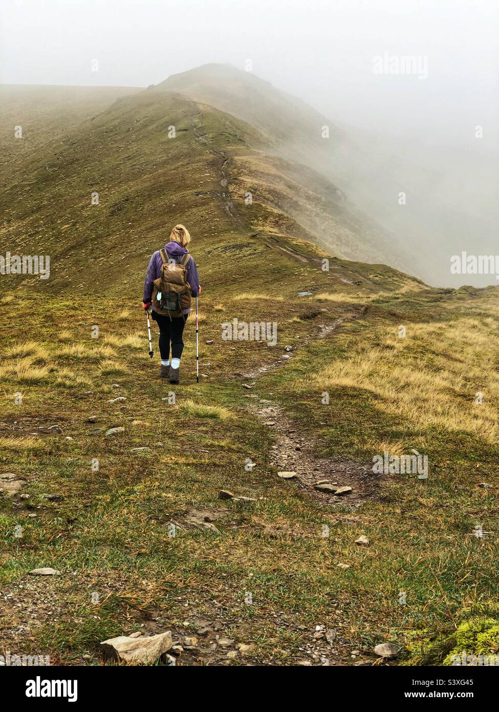 Walker on the ridge path with low lying cloud, Meall Corranaich, Killin ...