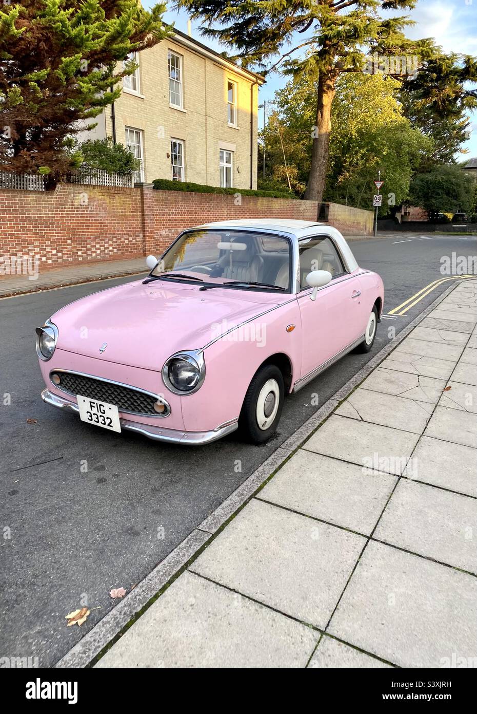 What a beautiful car! A pink Nissan Figaro parked in a residential street. Stock Photo
