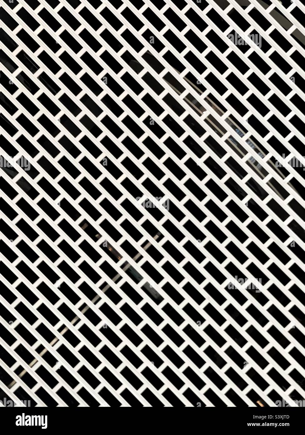 Pattern formed by the metal security grille on the entrance to a shop. No people. Stock Photo