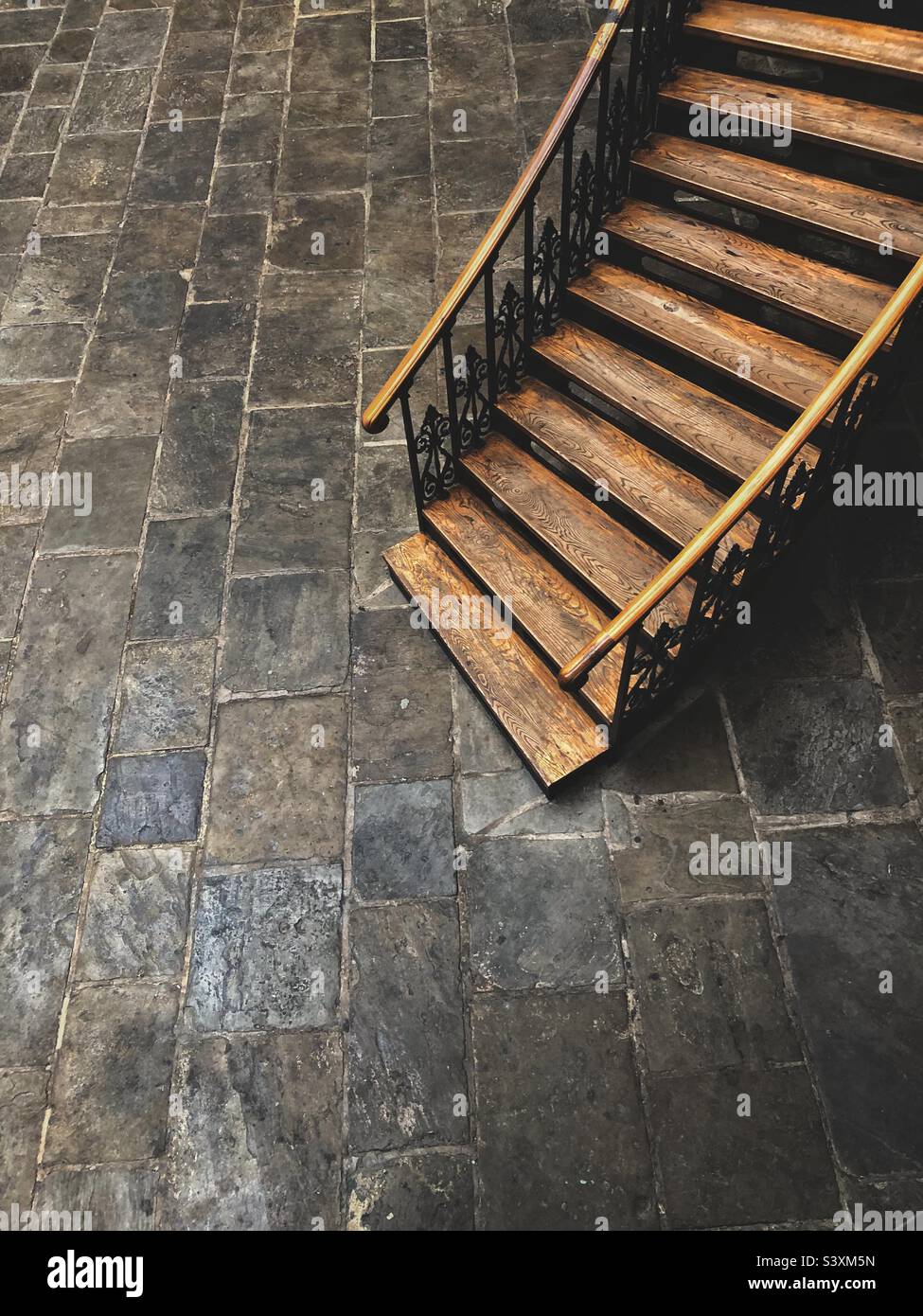 Hi angle view of an old of vintage wooden oak staircase with banisters winding down to a stone basement with copy space - Smartphone Captured Stock Image