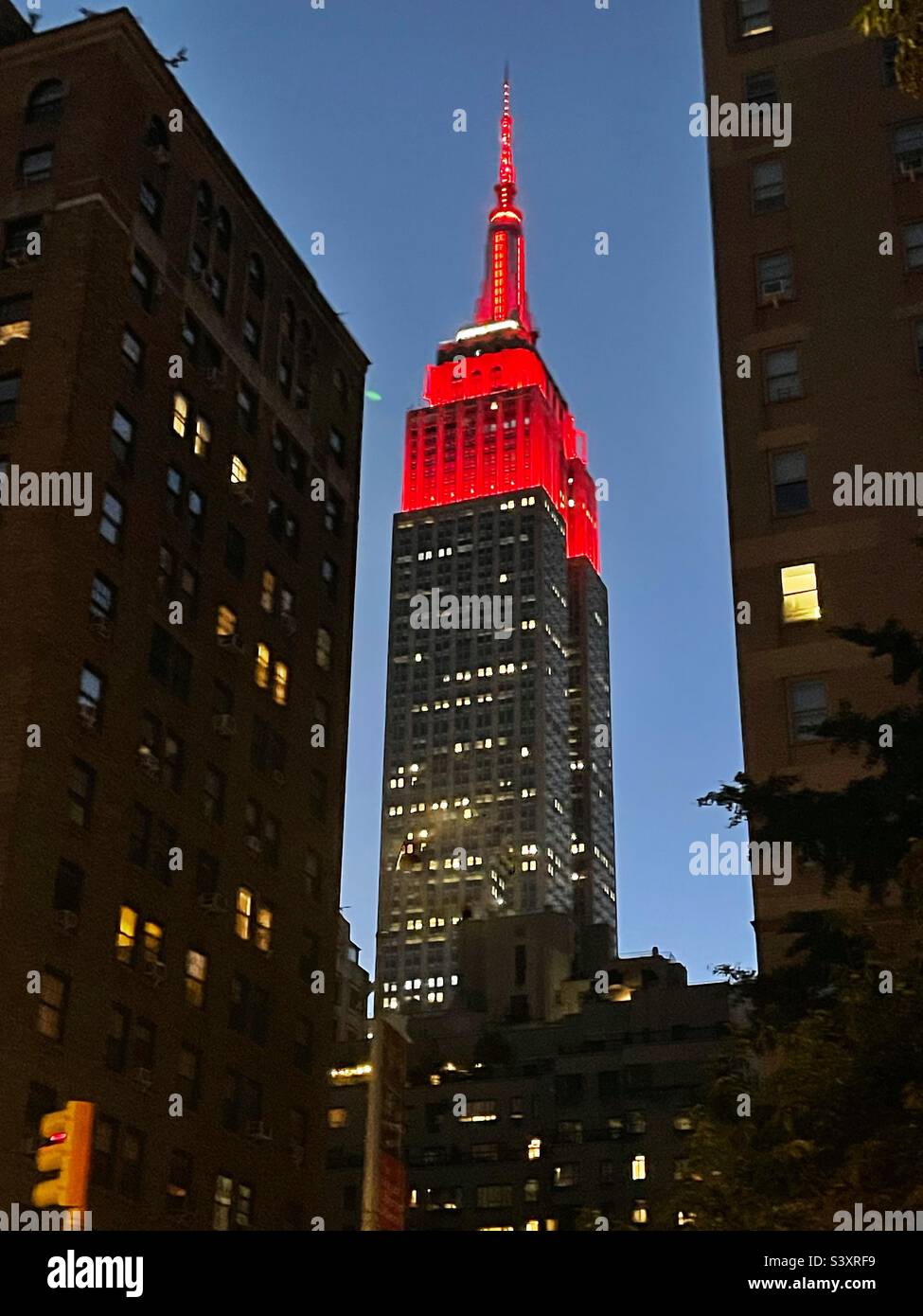 Red Tower lights on top of the Empire State building in the early evening as viewed from 35th St. and Park Avenue in New York City, USA, September 24, 2022 - Smartphone Captured Stock Image