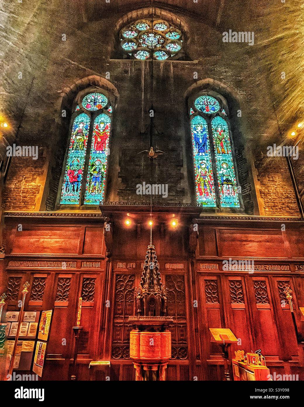 The font of 1907 is made up of polished marbles in the Holy Trinity Church in Folkestone, Kent. Grade II Listed historic building. Fine stained glass windows seen in situ 2022. - Smartphone Captured Stock Image