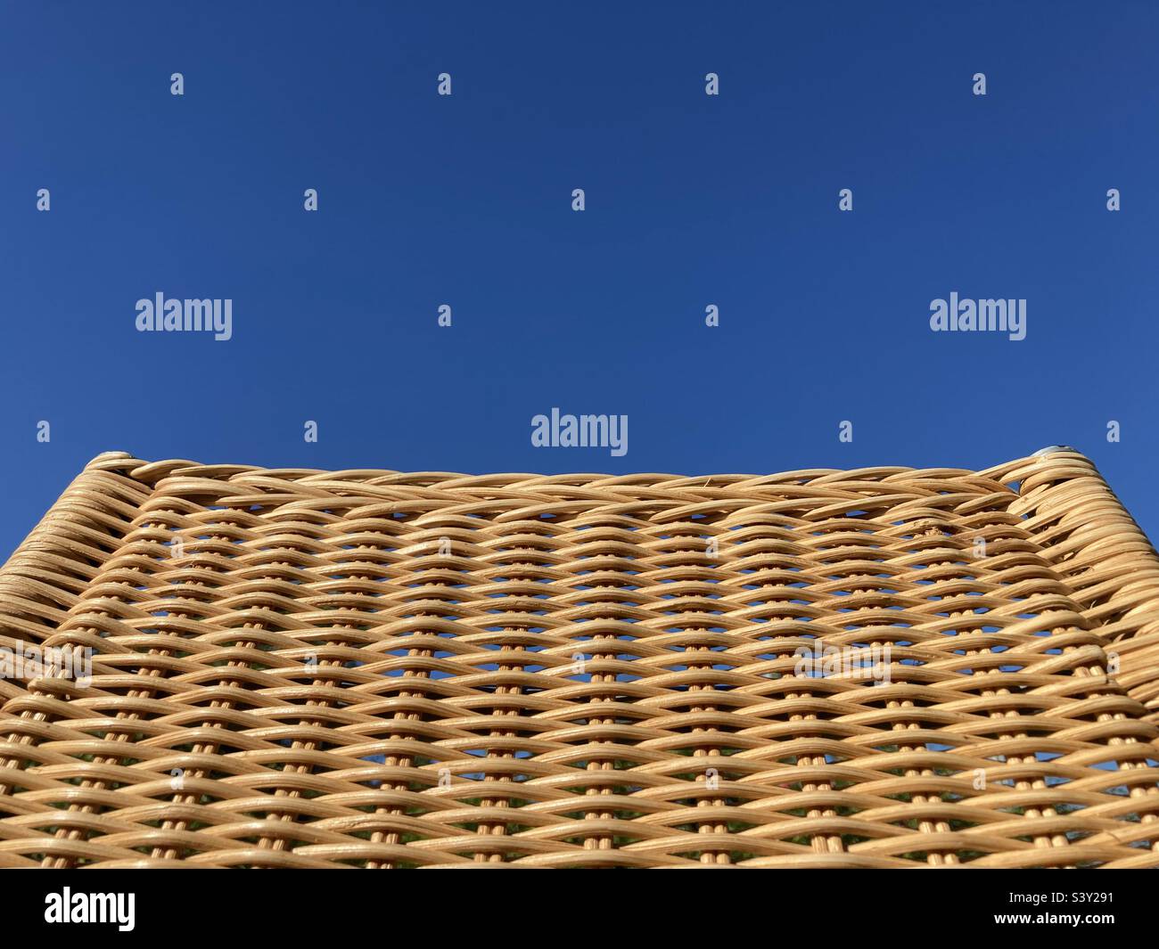 a tapered woven rattan pattern against a blue sky - Smartphone Captured Stock Image