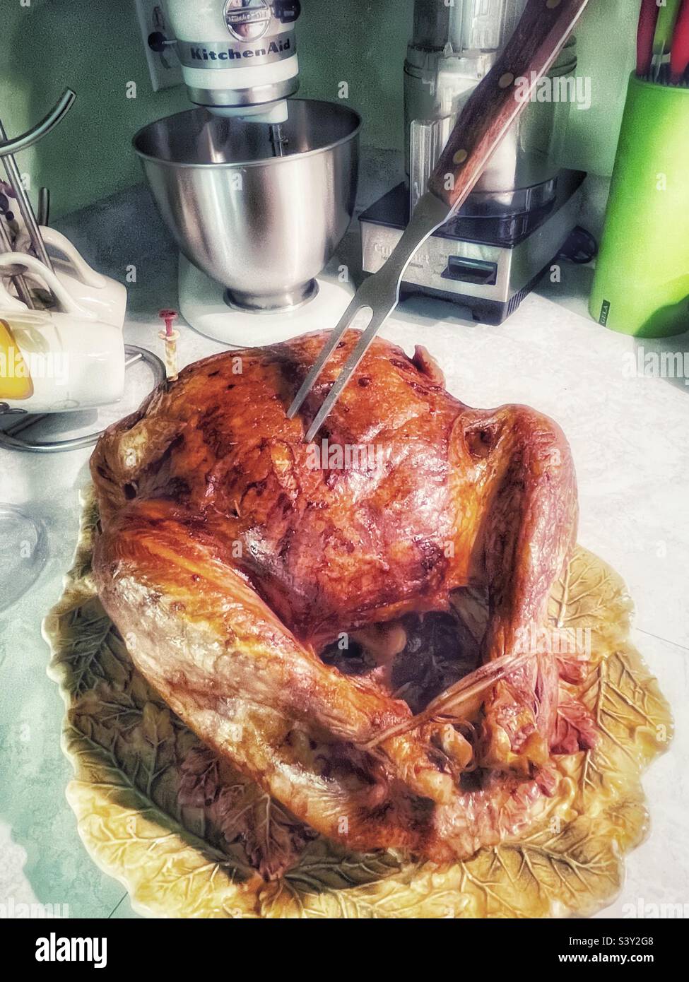 A turkey, cooked to a golden brown, is out of the oven and put upon the kitchen counter to rest and cool awhile before being carved on Thanksgiving day in Utah, USA. - Smartphone Captured Stock Image