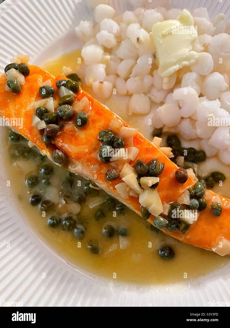 Close up of a gourmet meal of a salmon fillet piccata with a side dish of hominy grits, 2022, USA Stock Photo