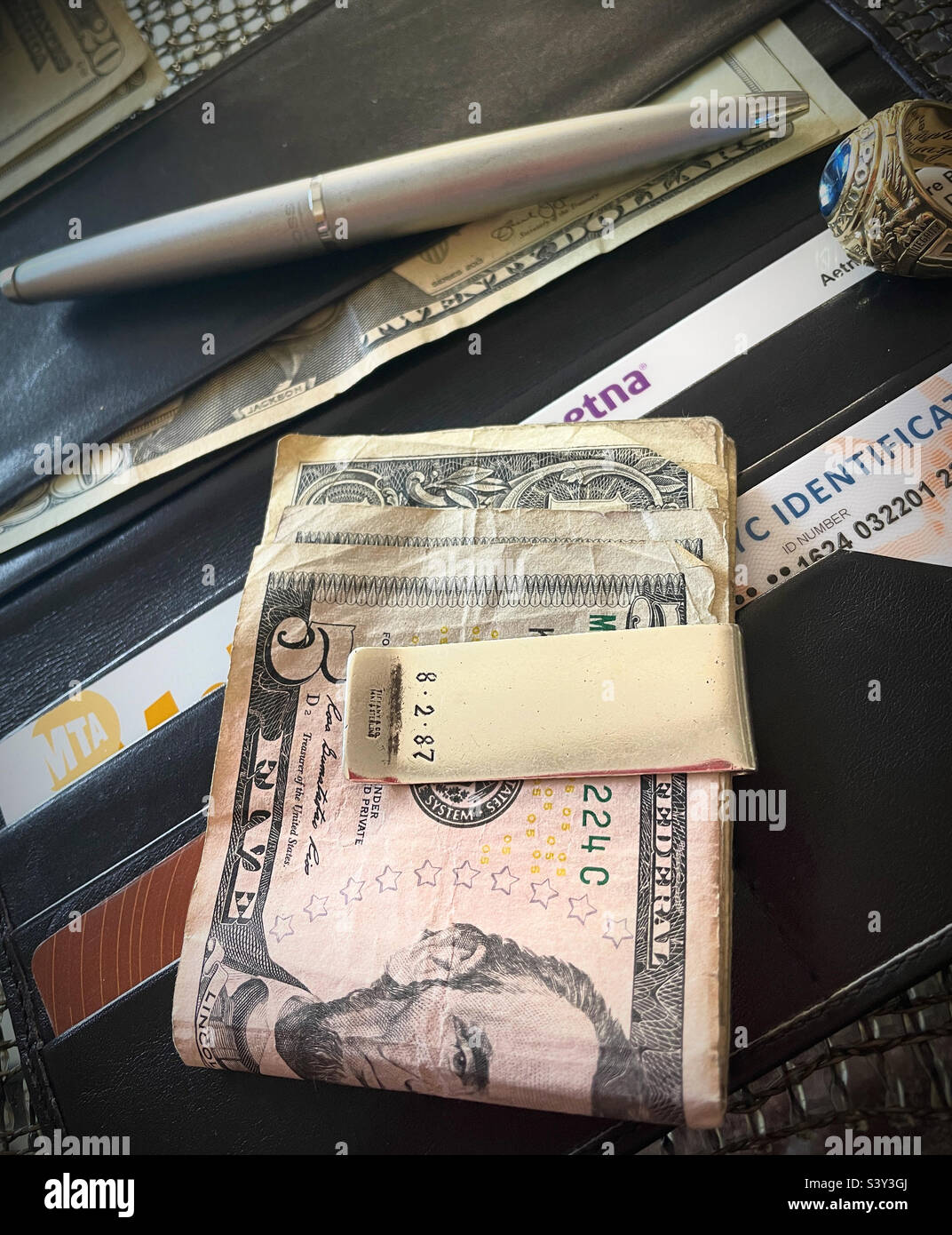 Still life Of a man’s money clip on top of his wallet, ballpoint pen and college ring, 2022, USA - Smartphone Captured Stock Image