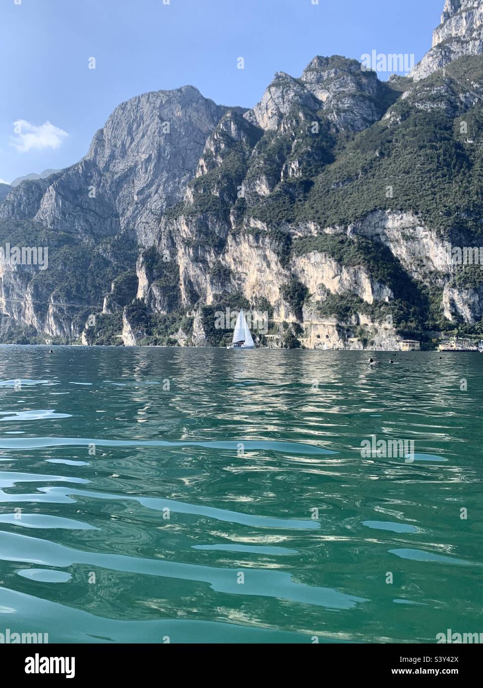 Small boat against large mountain lake Garda Italy Stock Photo