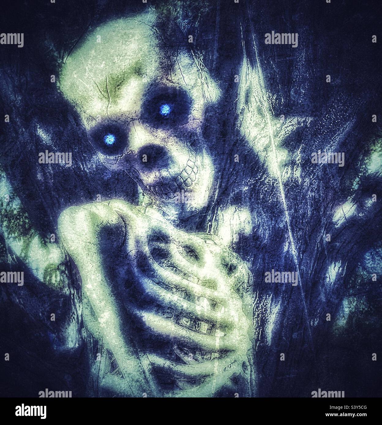 Life-sized skeleton being hanged on a tree each October as part of a Utah, USA yard’s decor as Halloween approaches. Demonic blue eyes added digitally. - Smartphone Captured Stock Image