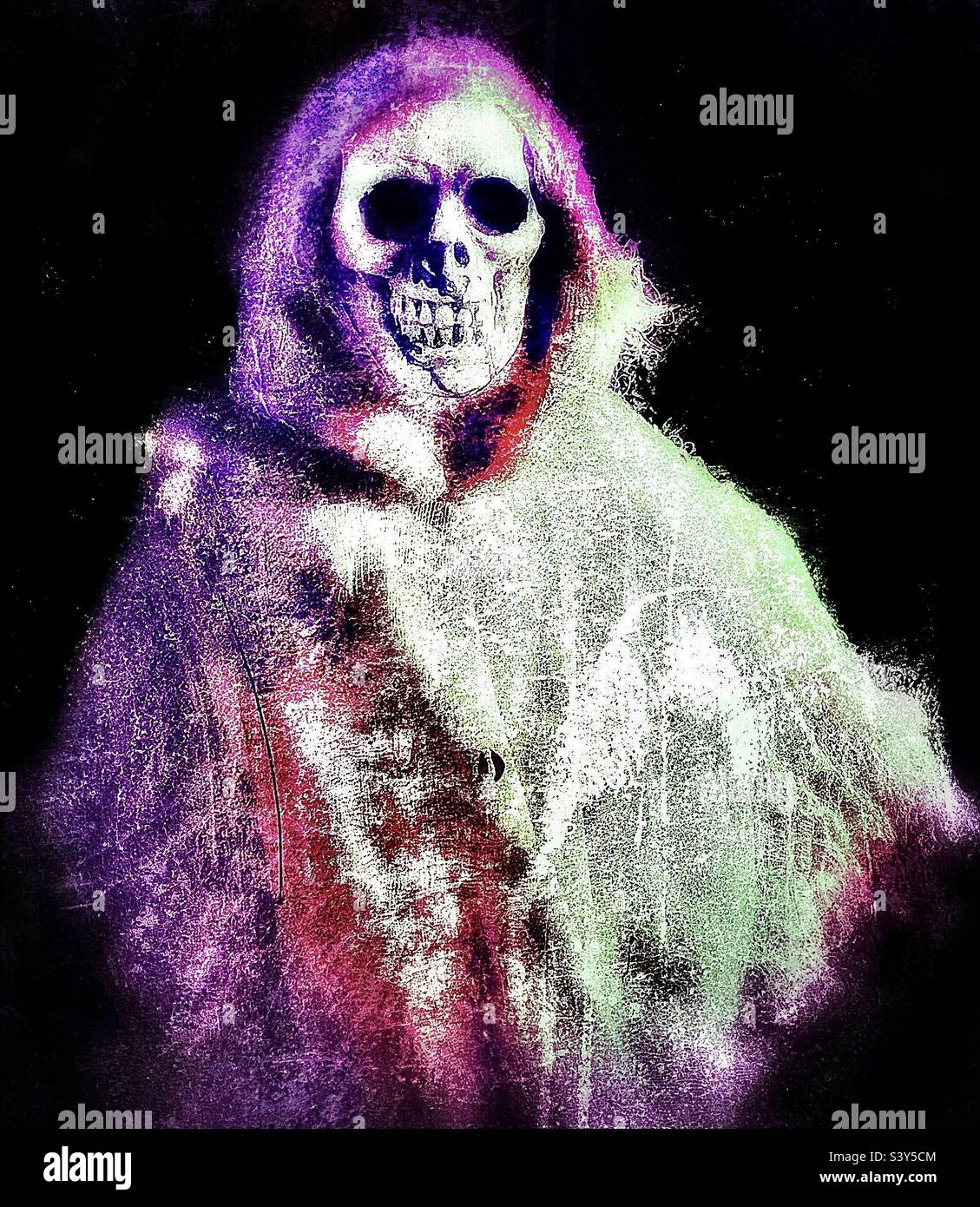 A skull-headed wraith or goblin hangs in a tree in a Utah, USA yard as part of their annual yard decoration as Halloween approaches. - Smartphone Captured Stock Image